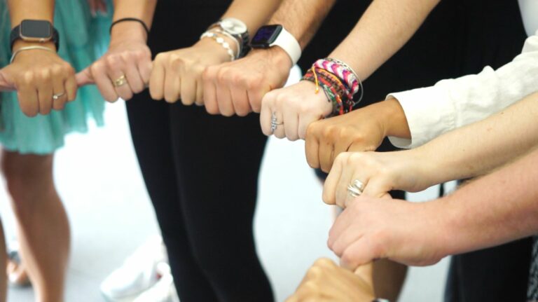 Close-up of hands forming a circle by holding each other's thumbs.