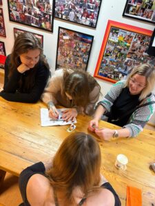 The project manager and the young people are chatting at the table while waiting for the game night to begin.